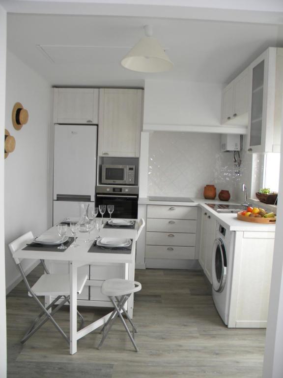 biała kuchnia ze stołem i kieliszkami do wina w obiekcie Serra da Pescaria House - Nazaré w mieście Nazaré