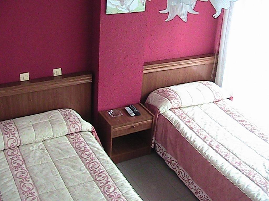 2 camas en una habitación con paredes moradas en Pensión Rada, en Solares