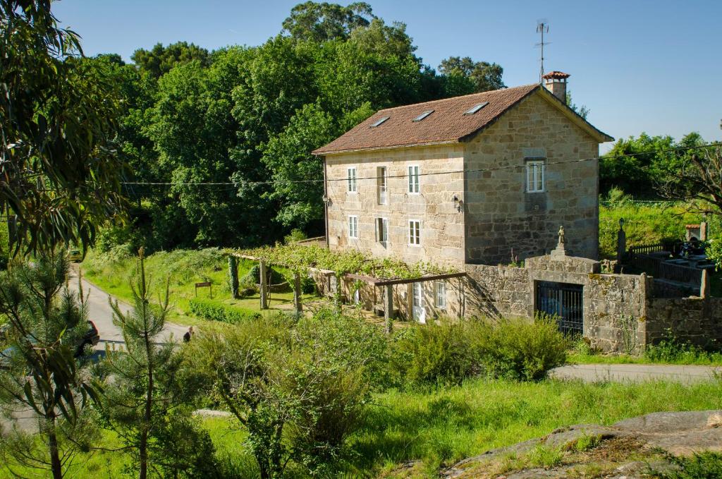 an old stone building in the middle of a field at Casa de Turismo Rural Os Petroglifos in Boiro