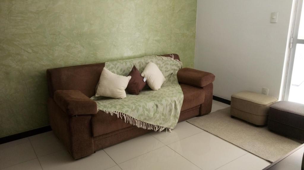 Apartamento Feliz في أراكاجو: أريكة عليها وسائد في غرفة المعيشة