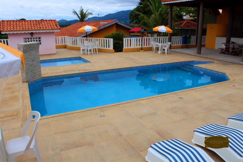 une piscine dans un complexe hôtelier avec des chaises longues et des parasols dans l'établissement Chalé Recanto Monte Sinai, à Piracaia