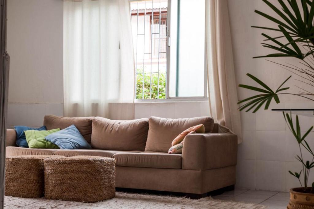 Sofá marrón en la sala de estar con ventana en Quarto em casa compartilhada, en Florianópolis