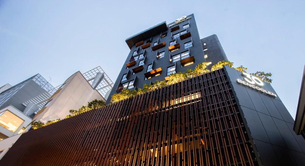 Un grand bâtiment avec des plantes en haut dans l'établissement 30 Bencoolen, à Singapour