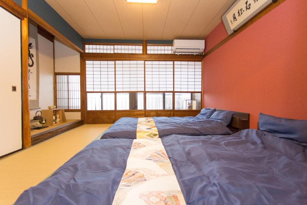 two beds in a room with red walls at Guest House Kyorakuya Kinkakuji in Kyoto
