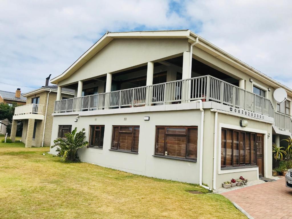 a white house with a balcony and a yard at Fairview Accommodation in Gansbaai