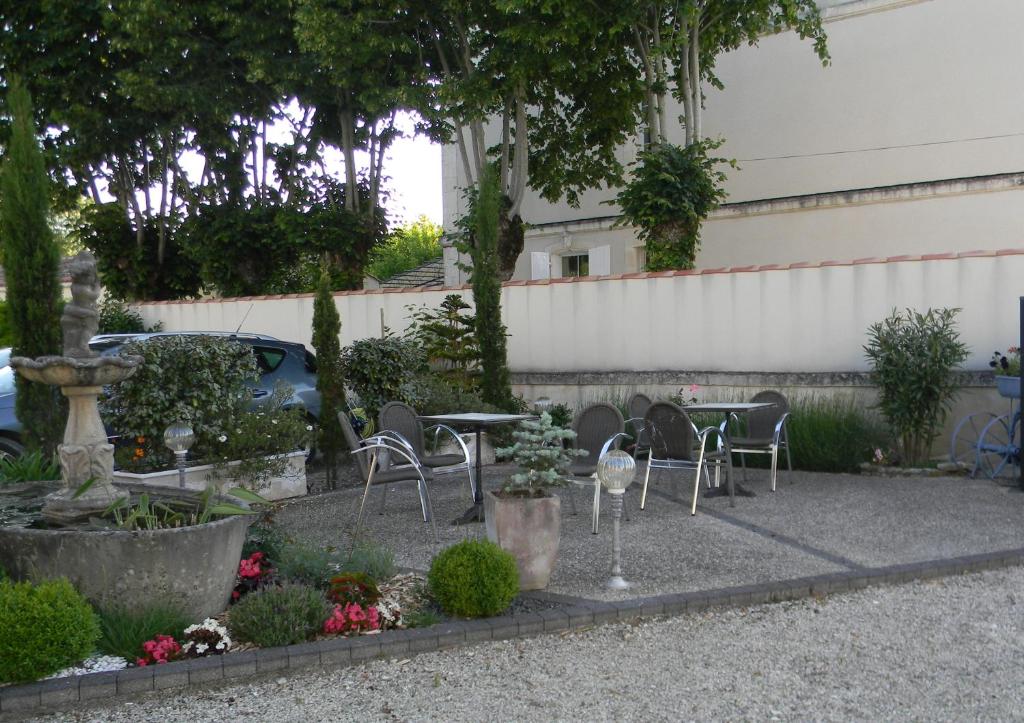 a garden with chairs and a table and a fountain at Le Logis d&#39;ANTIGNY in Val-du-Mignon