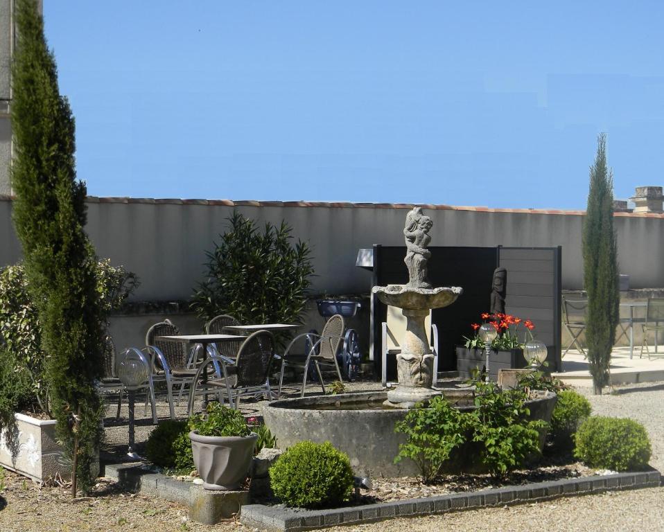 a fountain in a garden with tables and chairs at Le Logis d&#39;ANTIGNY in Val-du-Mignon