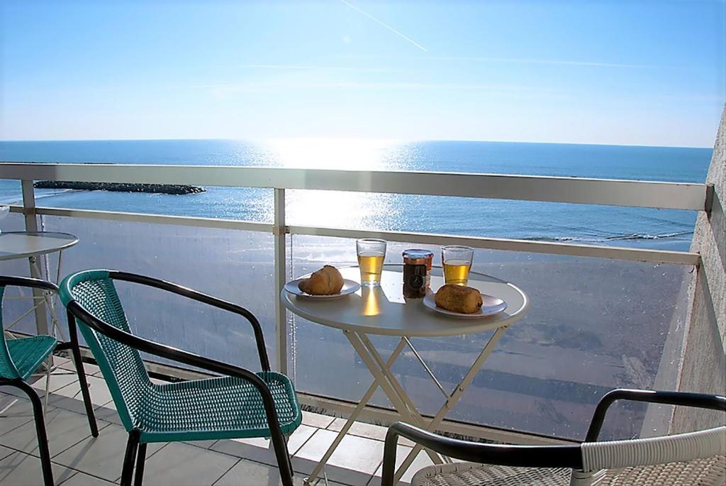 a table with two drinks on a balcony with the ocean at Superbe appartement sur la plage - Le Zénith in Palavas-les-Flots