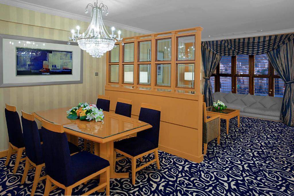 a dining room with a table and chairs and a chandelier at Makkah Towers in Mecca
