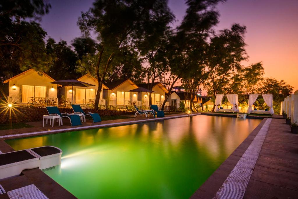 una piscina por la noche con luz verde en White Woods Resort, Morjim, en Morjim