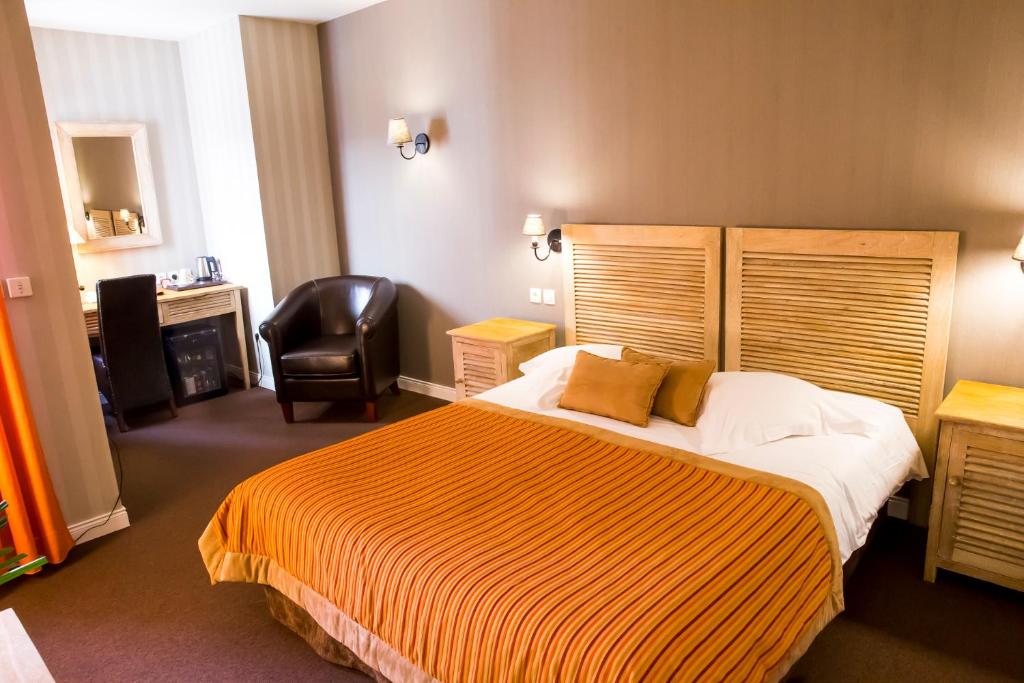 a hotel room with a bed and a chair at Almoria Hôtel & SPA in Deauville