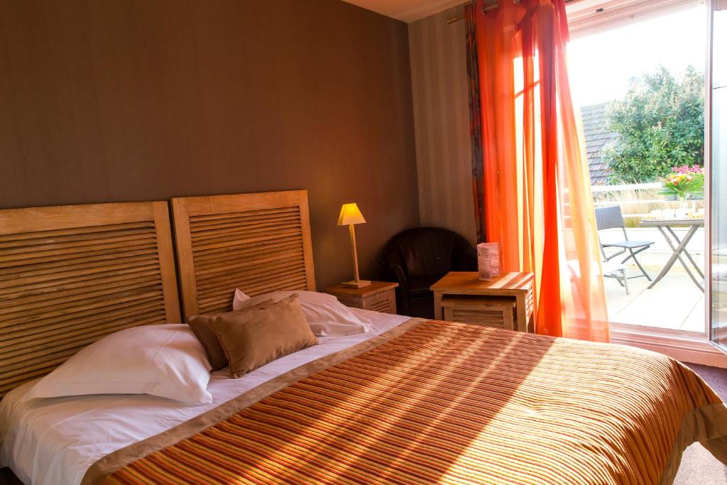 a bedroom with a large bed and a large window at Almoria Hôtel & SPA in Deauville