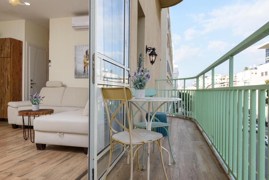 a balcony with a couch and a table and chairs at Sunset TLV Apartment - Ben Yehuda 175 in Tel Aviv
