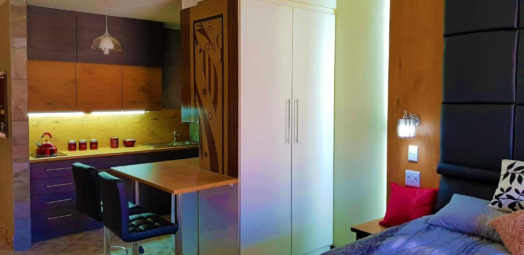 een slaapkamer met een bed, een bureau en een keuken bij Hyswan Self Catering Guesthouse in Krugersdorp