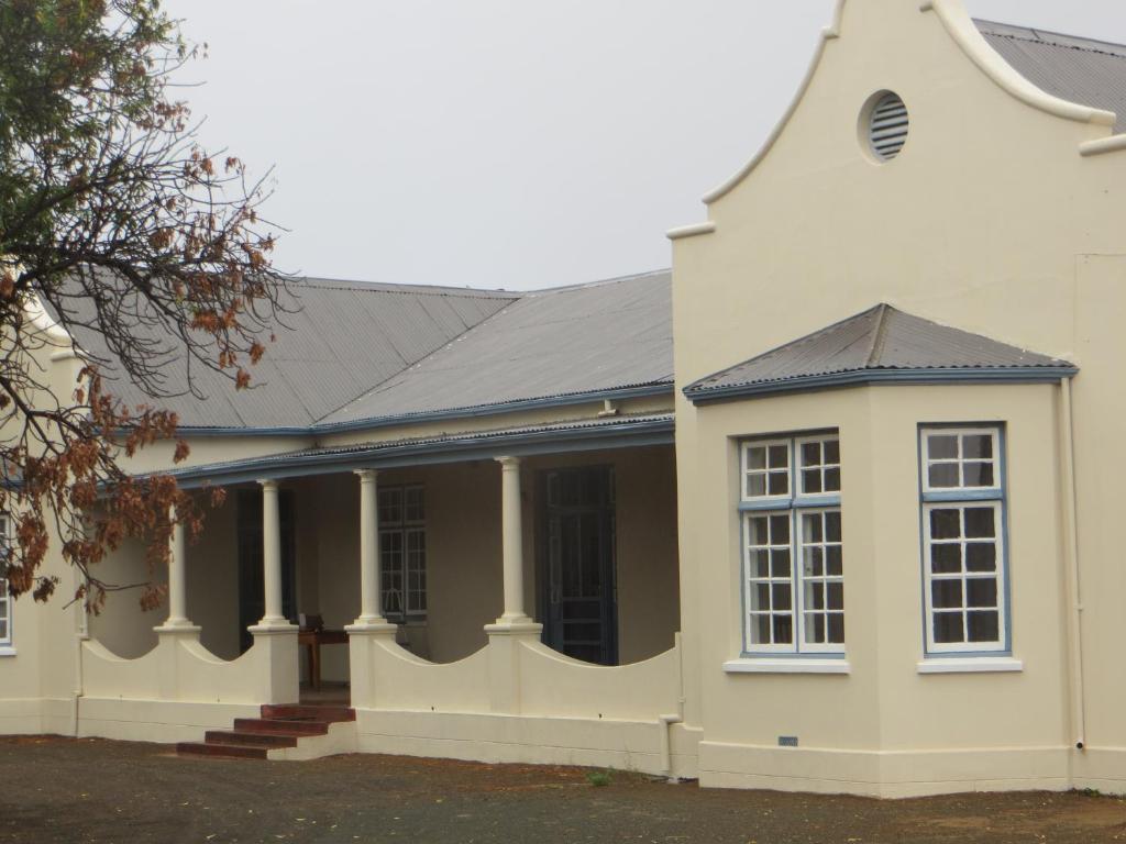 a white house with a black roof at Roode Bloem Farm House in Graaff-Reinet