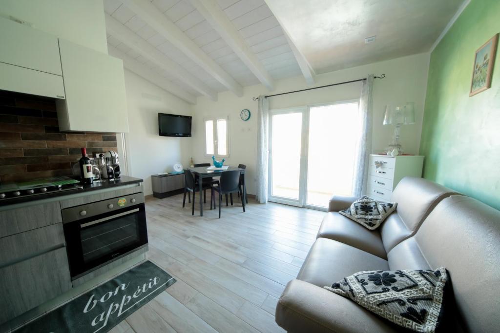 un soggiorno con divano, cucina e tavolo di Suite delle Rondini Apartment ad Alghero