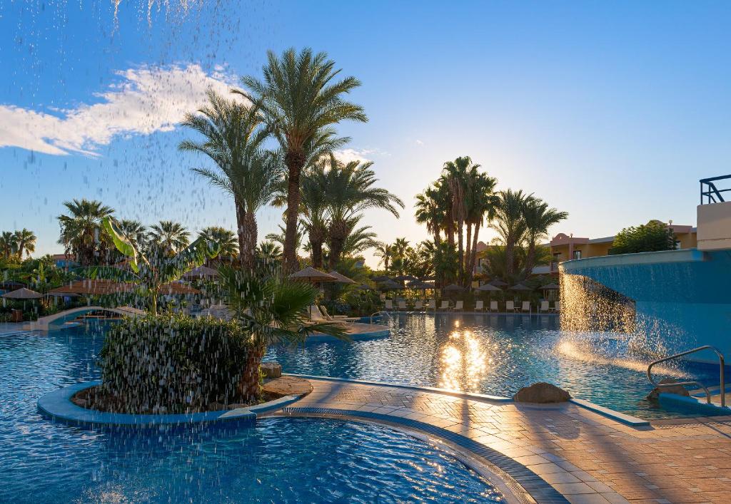 a pool at a resort with palm trees and a fountain at Atrium Palace Thalasso Spa Resort And Villas in Kalathos