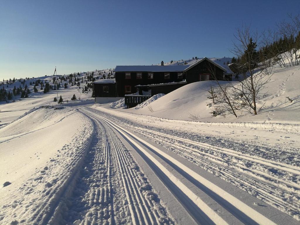 una strada ricoperta di neve con un edificio sullo sfondo di Sulseter Fjellstugu a Vinstra