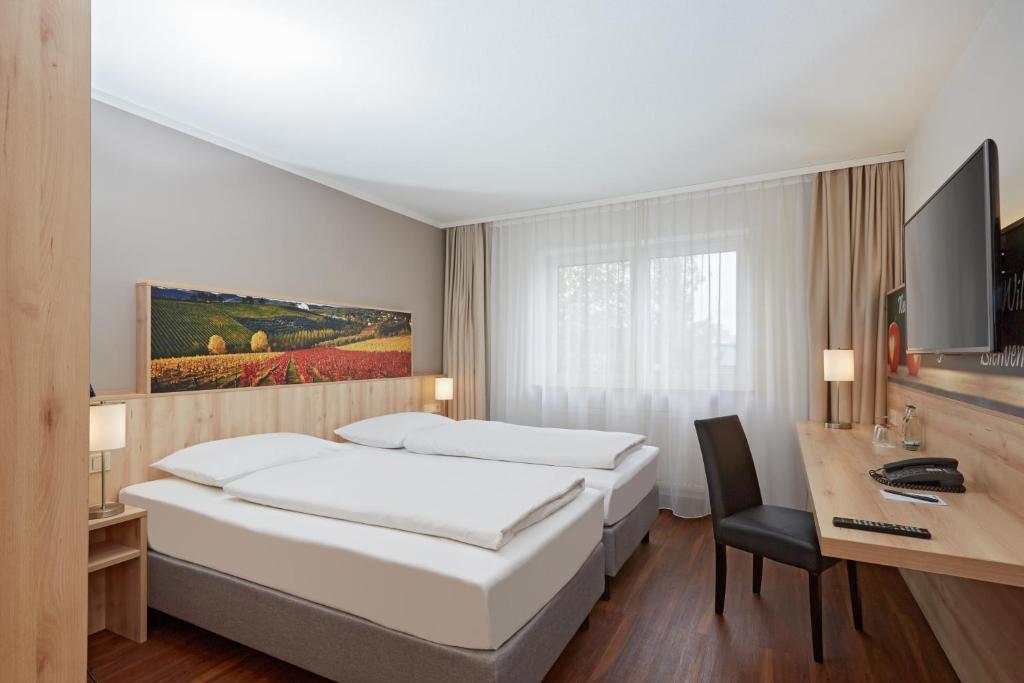 a hotel room with two beds and a desk at H+ Hotel Stuttgart Herrenberg in Herrenberg