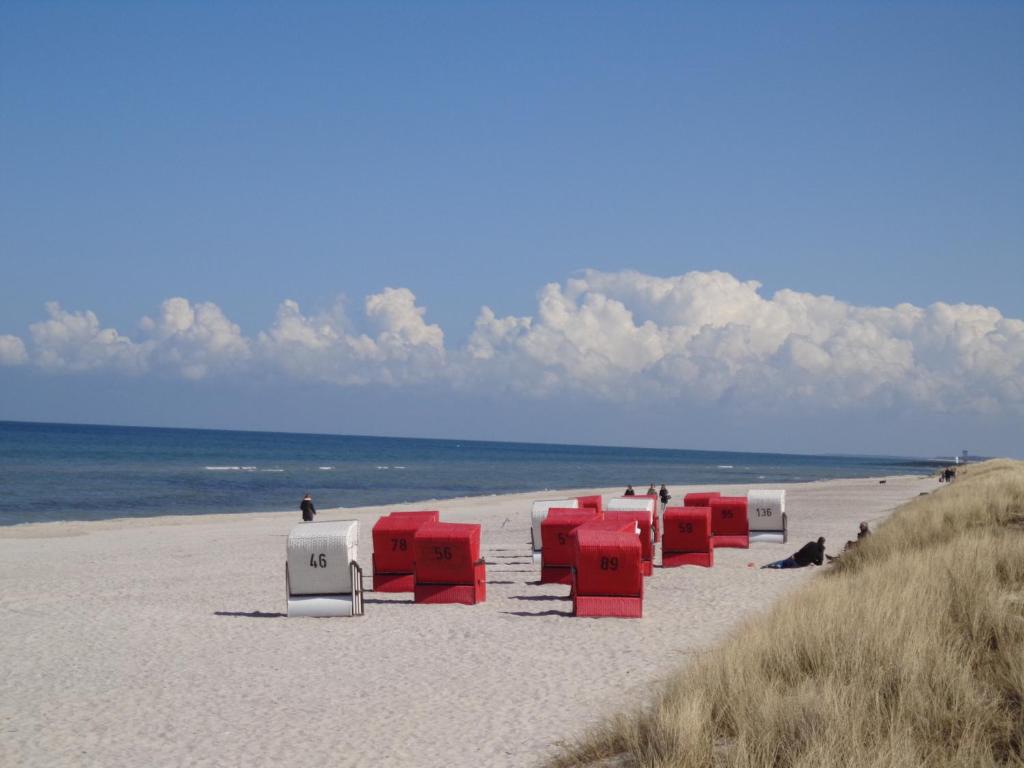 eine Reihe von roten und weißen Stühlen am Strand in der Unterkunft Darsskrabbe in Prerow