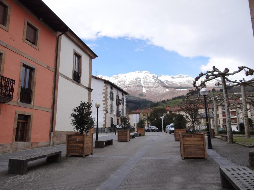 uma rua com bancos e uma montanha coberta de neve em Ostatu Zegama em Zegama