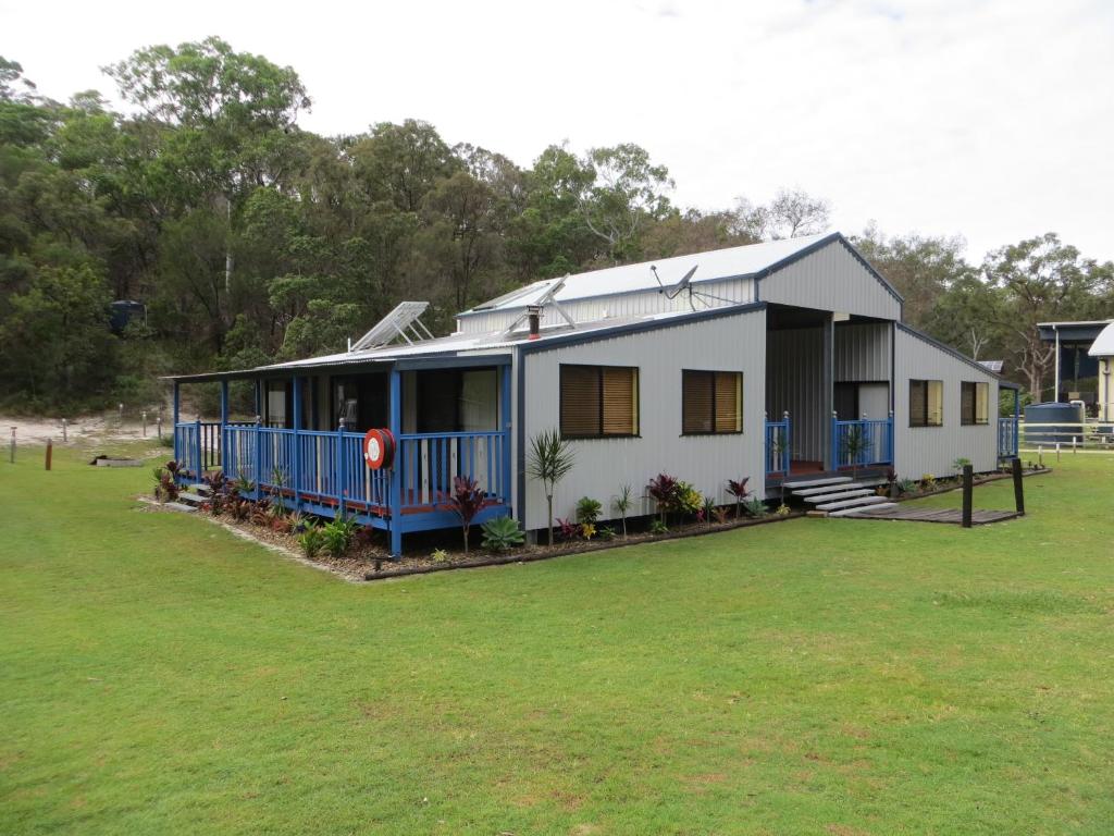 a small white house with a large yard at Orchid Beach Retreat Orchid Beach Fraser Island in Fraser Island