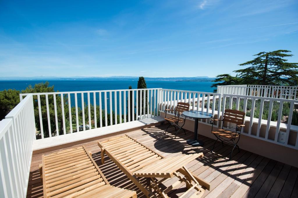 a wooden deck with chairs and a table on a balcony at Hotel Cliff Belvedere in Izola