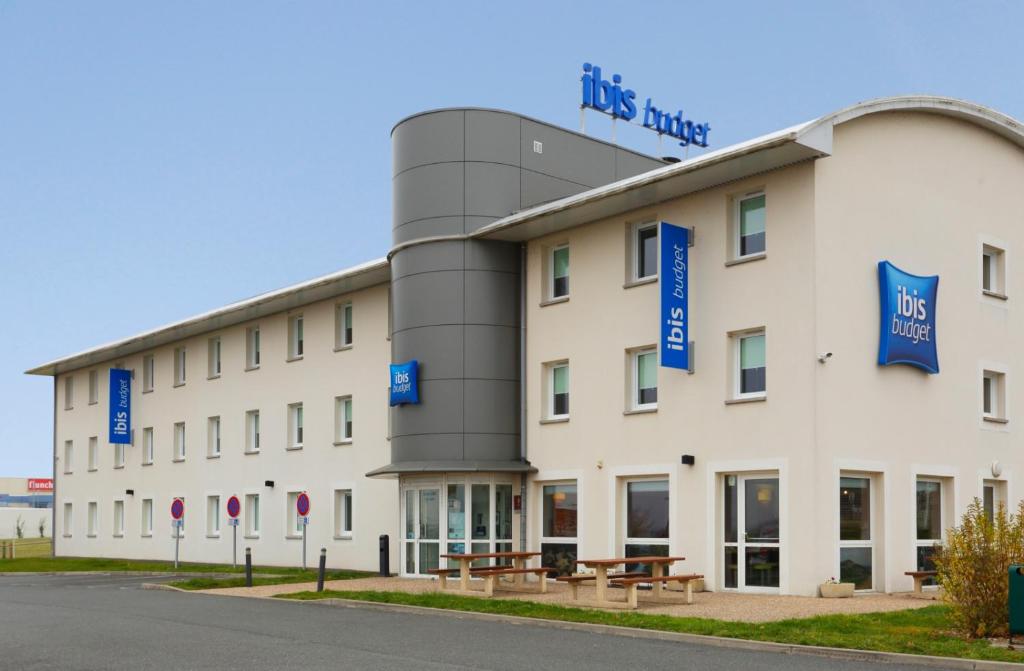 a large white building with blue signs on it at Hotel Ibis Budget Cosne Sur Loire in Cosne-Cours-sur-Loire