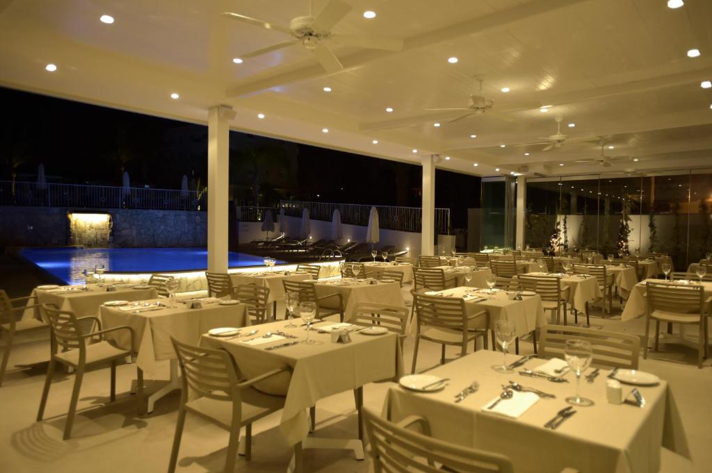 a restaurant with white tables and chairs in a room at Sunrise Gardens Aparthotel in Protaras