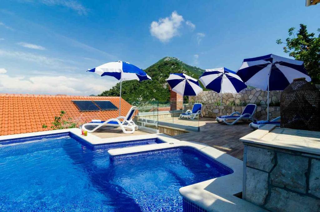 einen Pool mit Sonnenschirmen und Stühlen sowie einen Pool in der Unterkunft Adriatic-apartment & seaview pool in Sobra