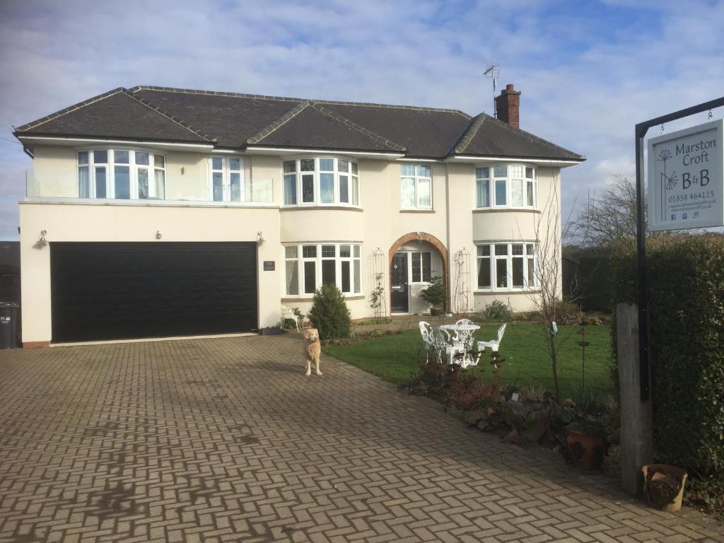 a man standing in front of a house with a garage at Marston Croft B&B in Market Harborough