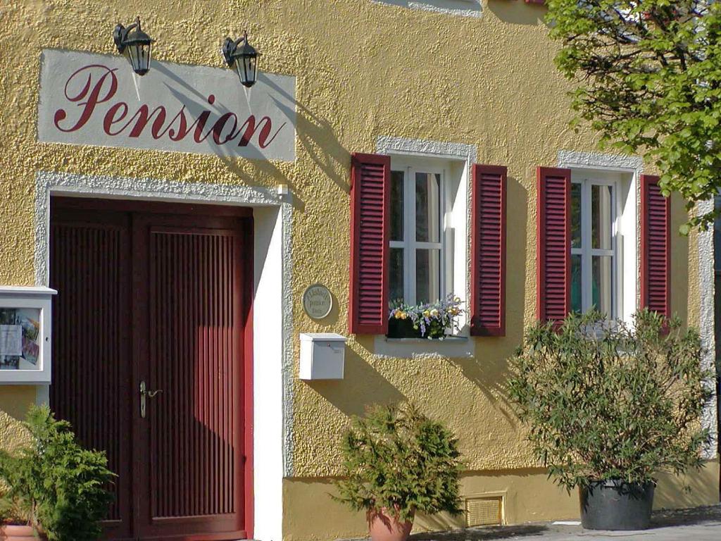 a yellow building with red shutters and a red door at Altstadtpension Dietz in Kelheim