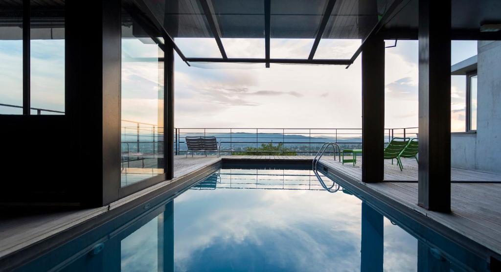 einem Pool mit Meerblick von einem Gebäude aus in der Unterkunft L'Ermitage Hôtel Cuisine-À-Manger in Saint-Cyr-au-Mont-dʼOr
