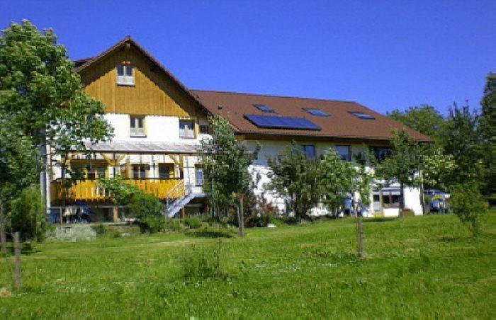une grande maison avec des panneaux solaires au-dessus d'un champ dans l'établissement Wohnung 5 Morgensonne, à Hergensweiler