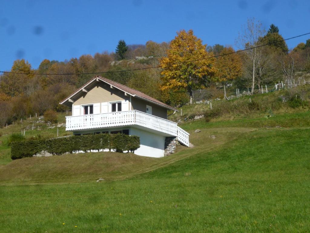 une maison blanche au sommet d'une colline herbeuse dans l'établissement La Bresse Hautes Vosges Chalet Le Podent, à La Bresse