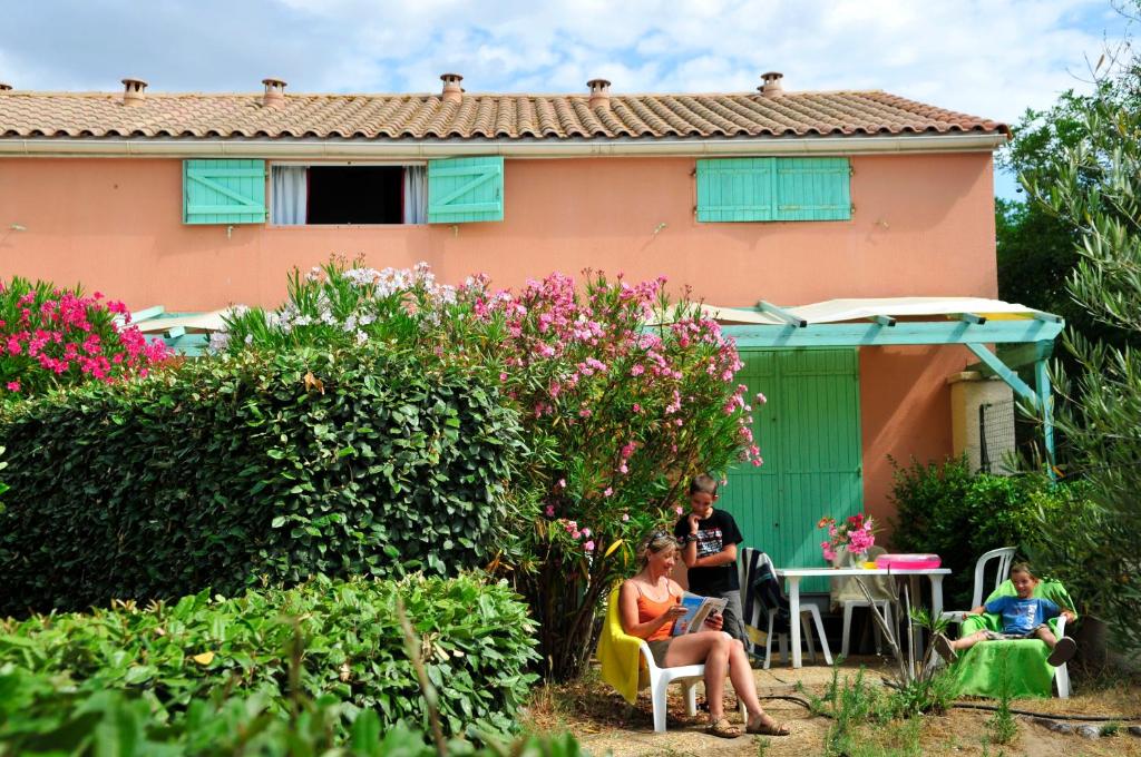 un grupo de personas sentadas fuera de una casa en Résidence Goélia Sun Village, en Portiragnes