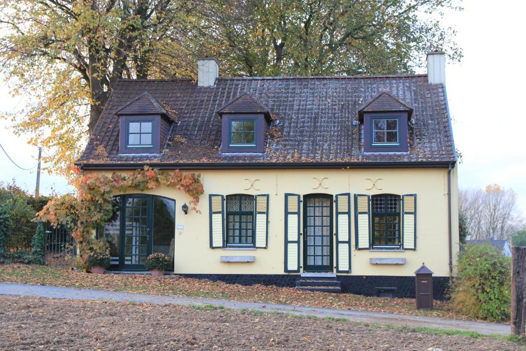 una antigua casa blanca con ventanas negras en Vakantiehuis Charmant, en Brakel