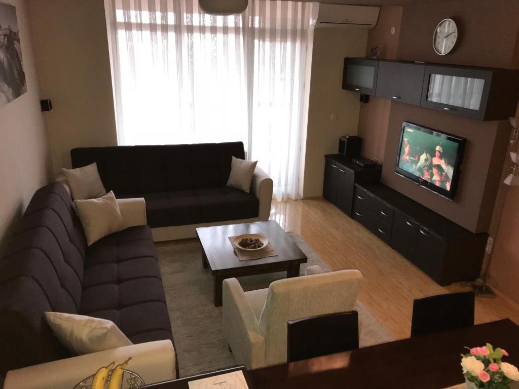 a living room with a couch and a tv at Redon's City Center Apartment in Prishtinë