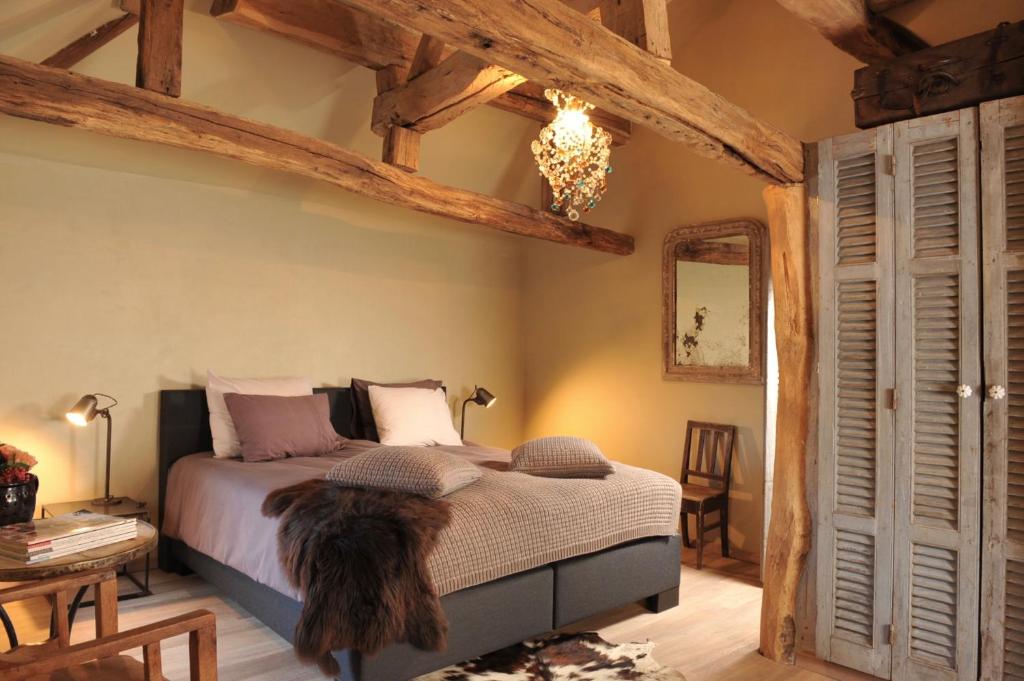 een slaapkamer met een groot bed en houten balken bij B&B Sapere in Genoelselderen