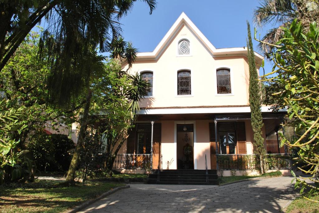 una casa blanca con árboles delante de ella en Hotel Casablanca Koeler, en Petrópolis