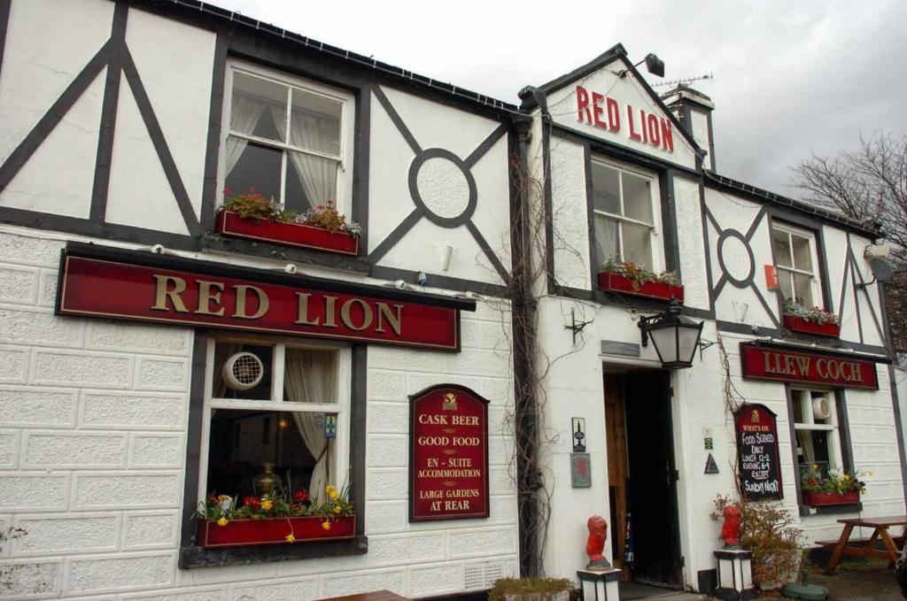 a white building with red lion signs on it at The Red Lion Inn & Restaurant in Prestatyn