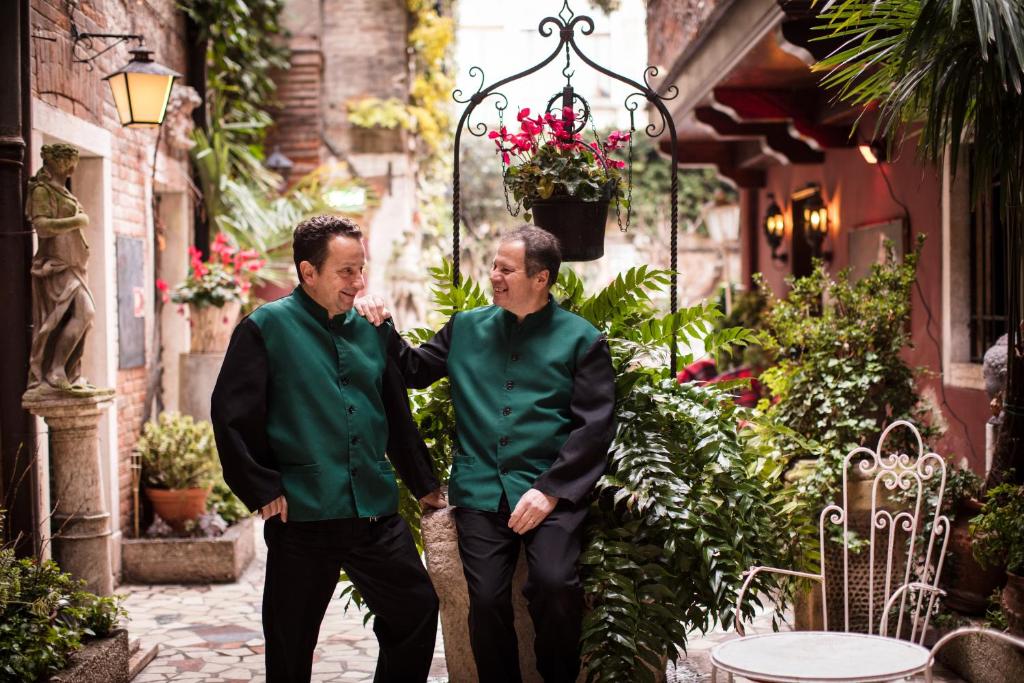 two men in green shirts walking down a street at Hotel Flora in Venice