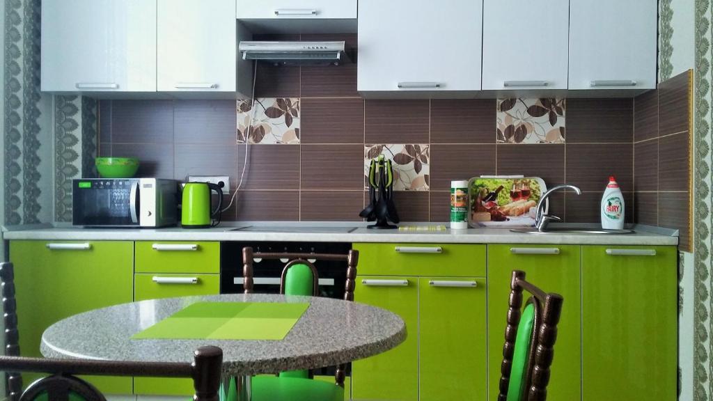 a kitchen with green cabinets and a small table at Однокомнатная in Astana
