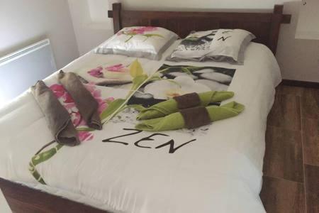 Una cama con sábanas blancas y flores. en Chambre ZEN en Panazol