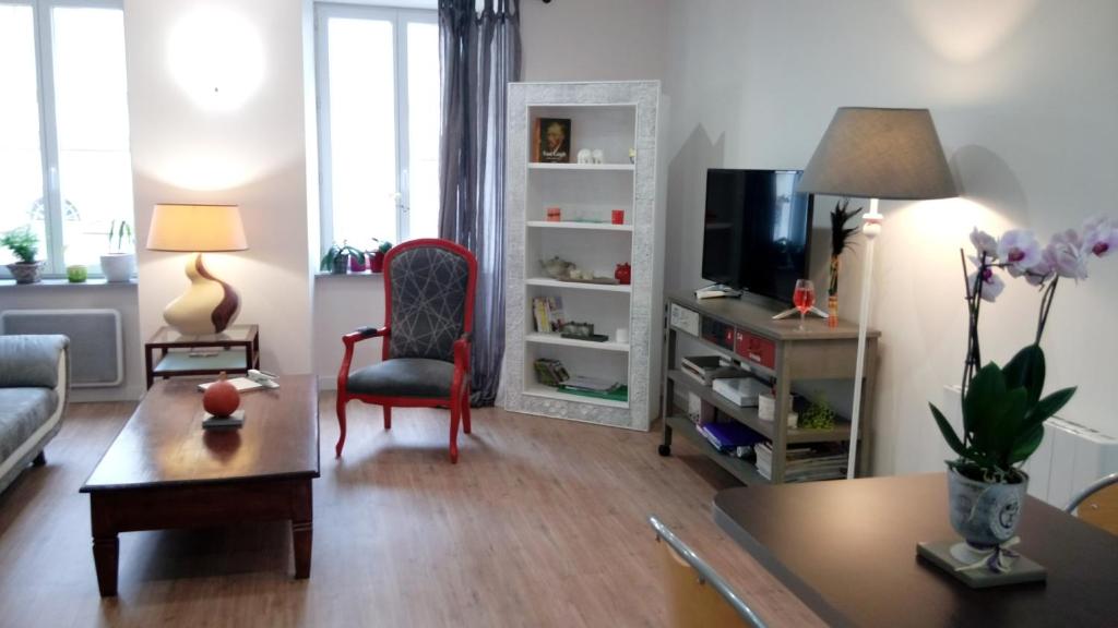 een woonkamer met een bank en een tv bij Les Chambres Hautes d'Anastasia in Rodez