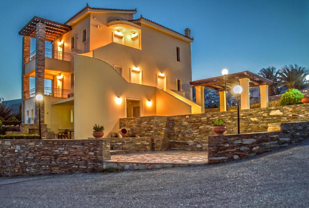 una casa grande con una pared de piedra y un camino de entrada en Villa View Studios, en Ándros