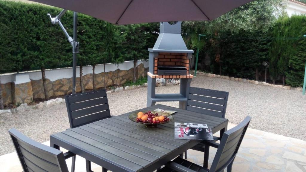 einen Holztisch mit einer Schale Obst und einem Sonnenschirm in der Unterkunft Rentalmar Casa Horus in Miami Platja
