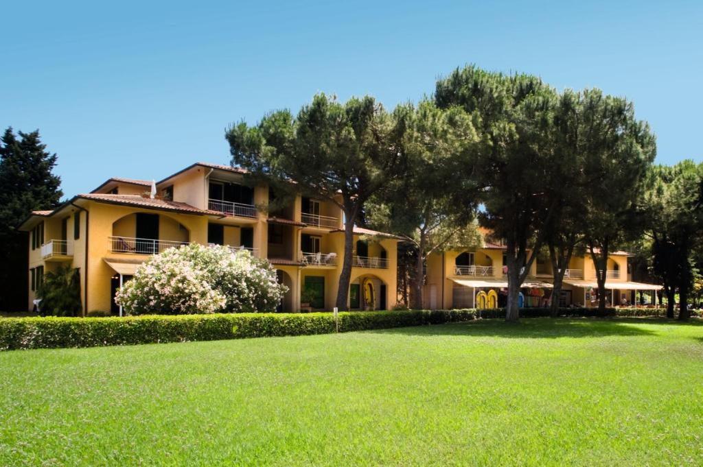 una gran casa amarilla con árboles en el patio en Residence Golfo Della Lacona, en Lacona