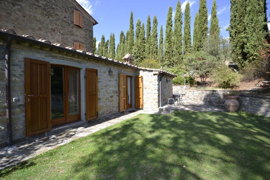 una casa in pietra con un prato davanti di Appartamento Valentino a Cortona