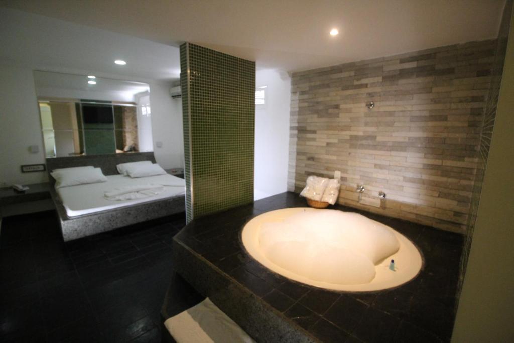a bathroom with a large bath tub and a bed at Hotel Colonial (Adult Only) in Olinda